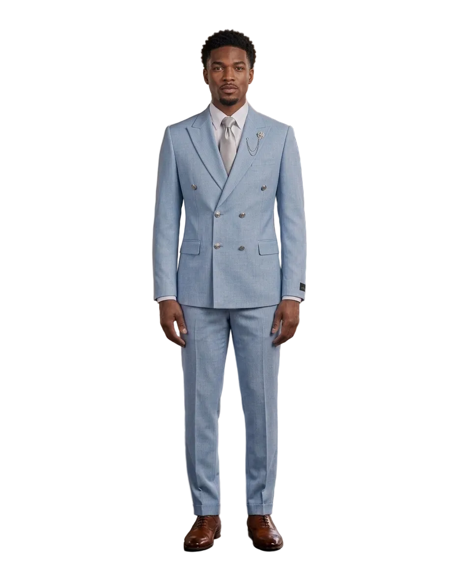 A man wearing a light blue double-breasted suit, white dress shirt, and white tie stands in a modern loft-style room with wood paneling, brick walls, and large windows.