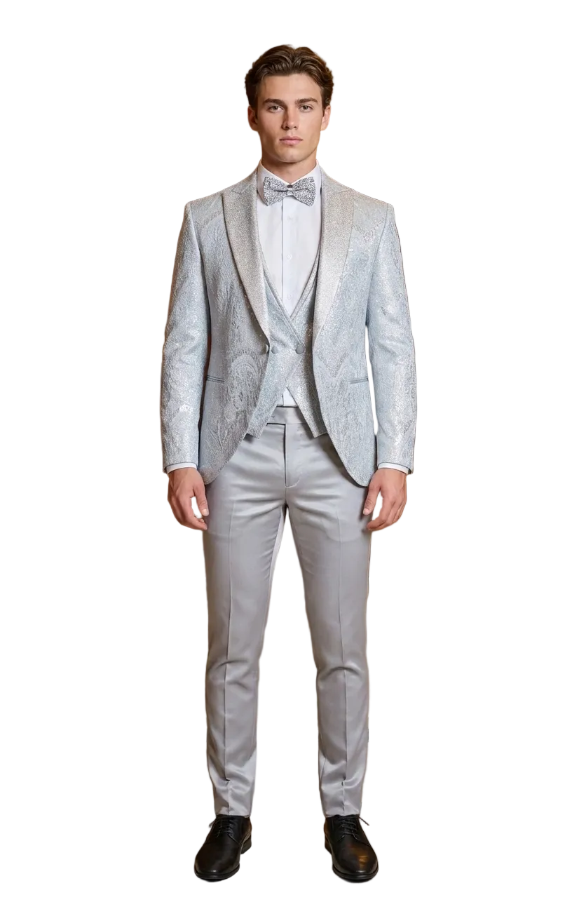 Man in a light gray suit standing in an elegant room with chandeliers and chairs.